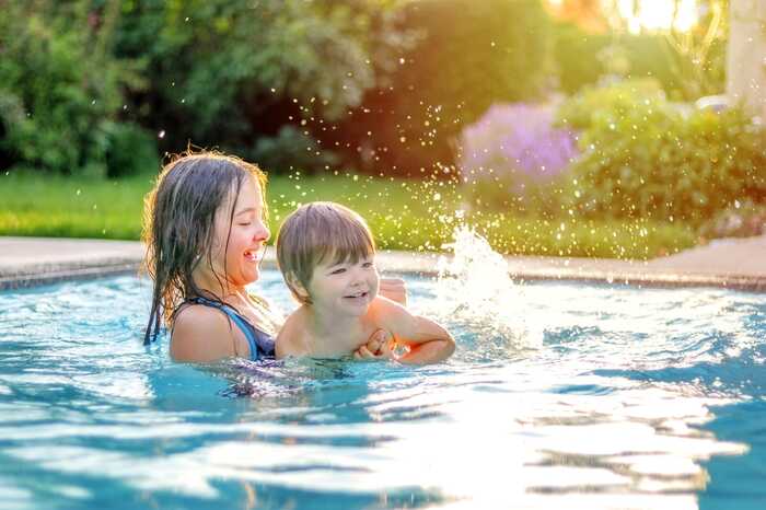 Children splashing and laughing in an outdoor swimming pool