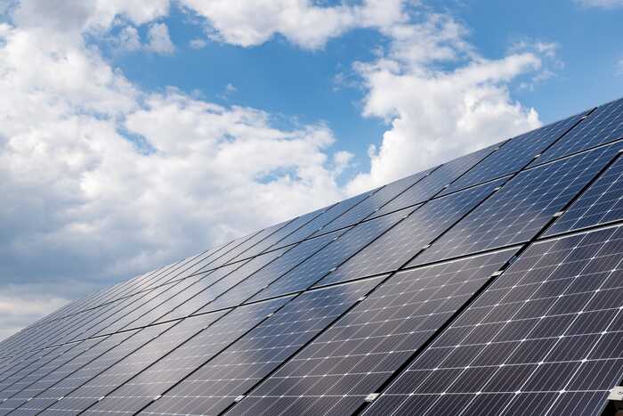 Solar panels on a roof, with a bit of blue sky but mostly clouds