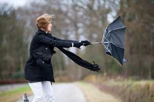 Woman struggling with her inside-out umbrella in high winds Woman struggling with her inside-out umbrella in high winds
